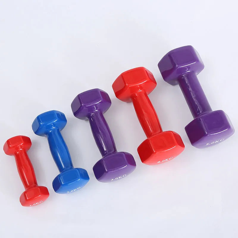 Set of bright colour plastic fitness dumbbells in various weights on a floor.