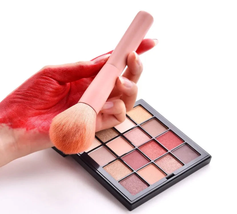 Ten professional makeup brushes with wooden handles arranged by size for different cosmetic applications