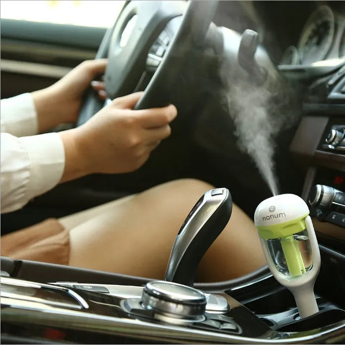 Compact blue portable car humidifier and air freshener diffuser on a car dashboard.