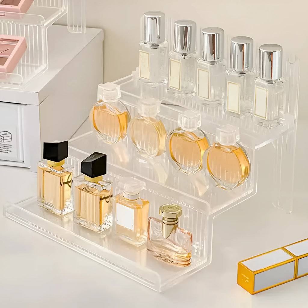 Transparent acrylic cosmetics storage rack with detachable shelves, displaying perfume bottles and small accessories