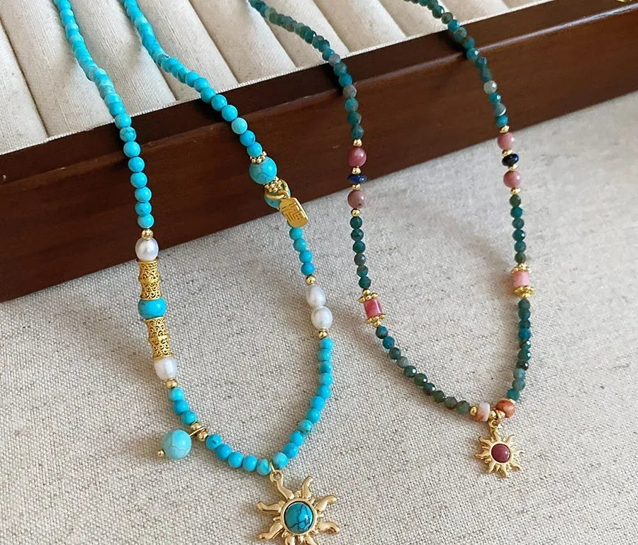 Freshwater pearl necklace with blue stone sun pendant on a gold-tone adjustable chain.