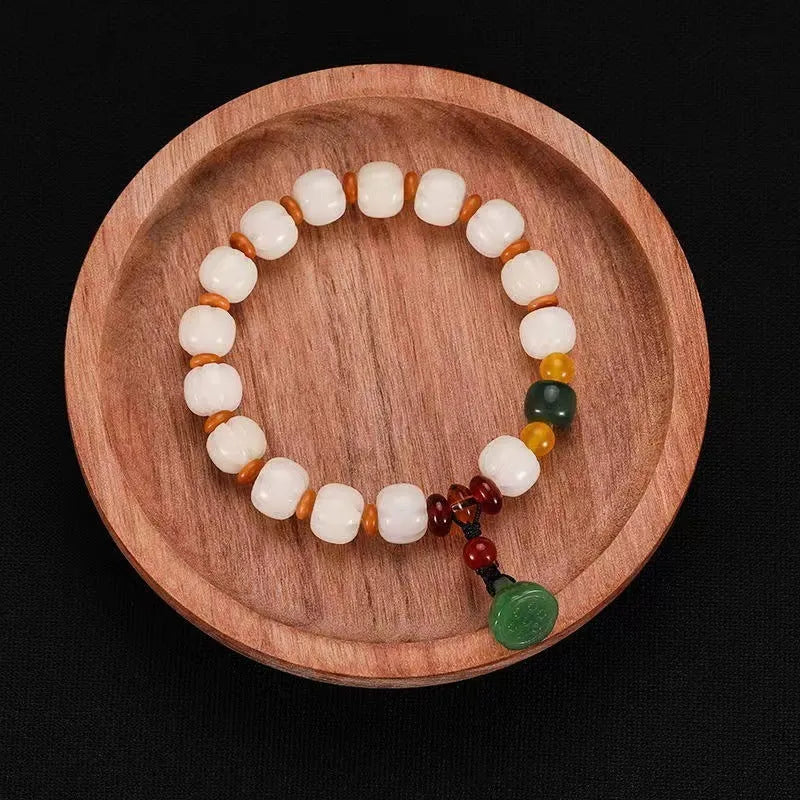Carved Bodhi root bracelet with white jade, lotus, and pumpkin beads in various sizes.