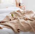 Nordic fringed knit ball acrylic blanket in beige colour on sofa