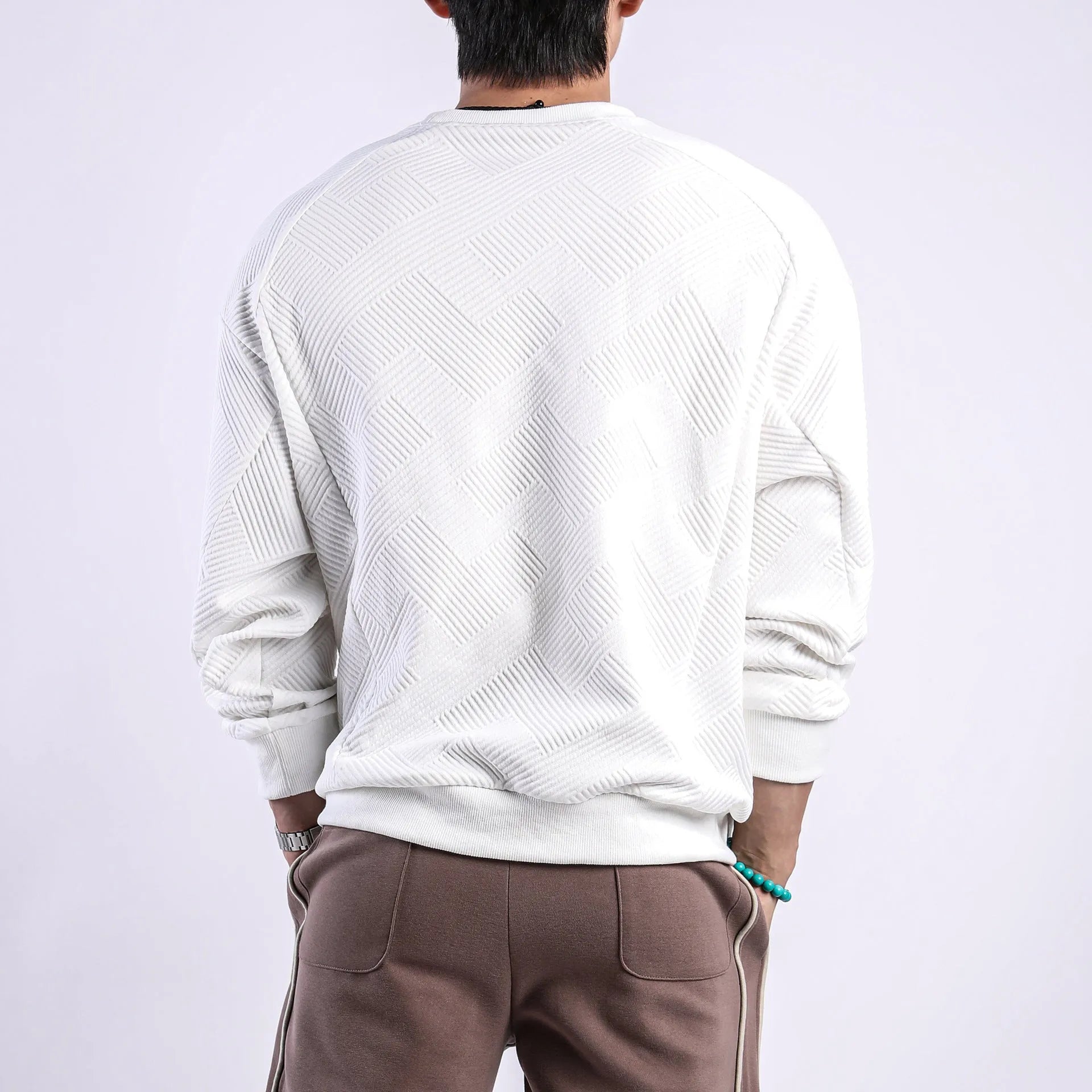 Men's loose fit long-sleeved twill jacquard sweater in a solid colour on a hanger