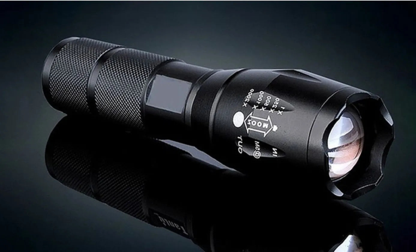 Black aluminum alloy zoom flashlight with adjustable head for focus, shown with beam reaching into distance.