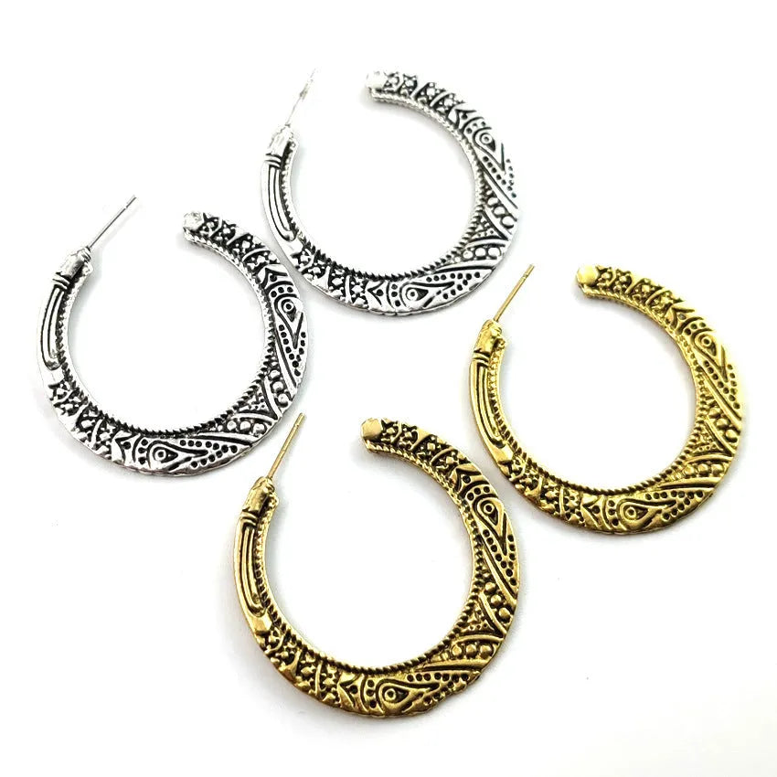 A pair of vintage-style C-shaped alloy earrings with detailed street shot engraving, shown in bronze finish.