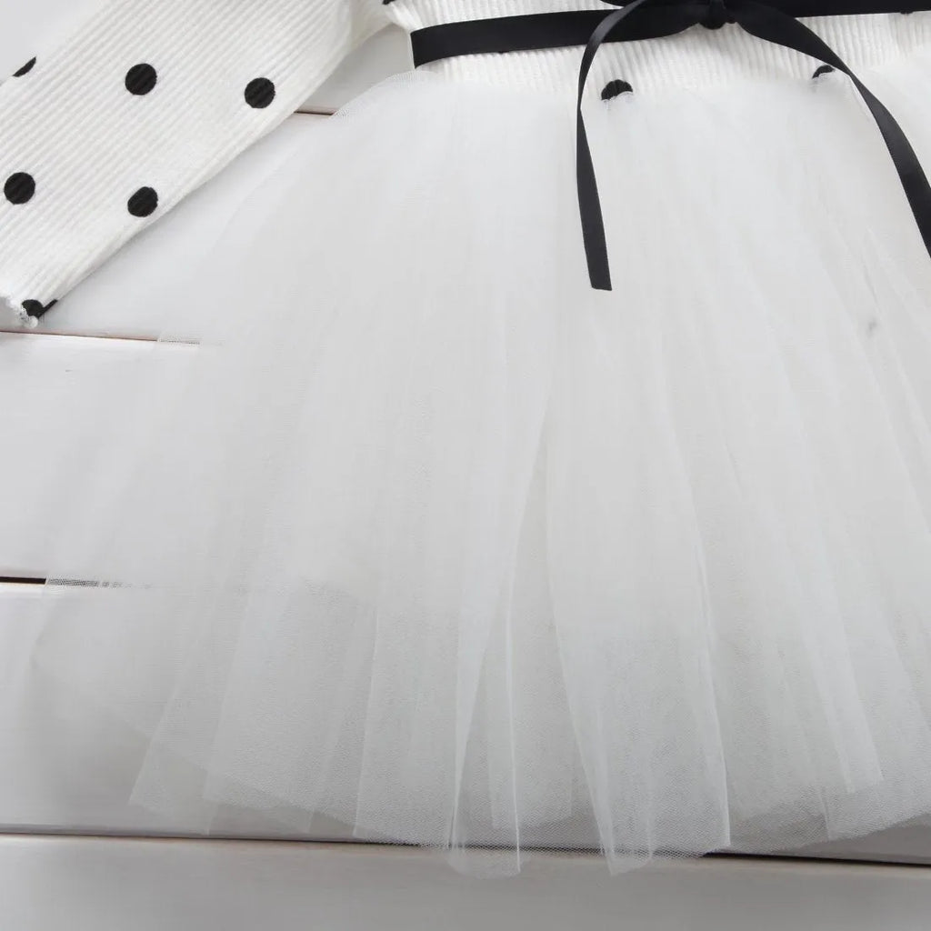 Baby girl wearing a long sleeve white lace tutu dress for a birthday or christening.