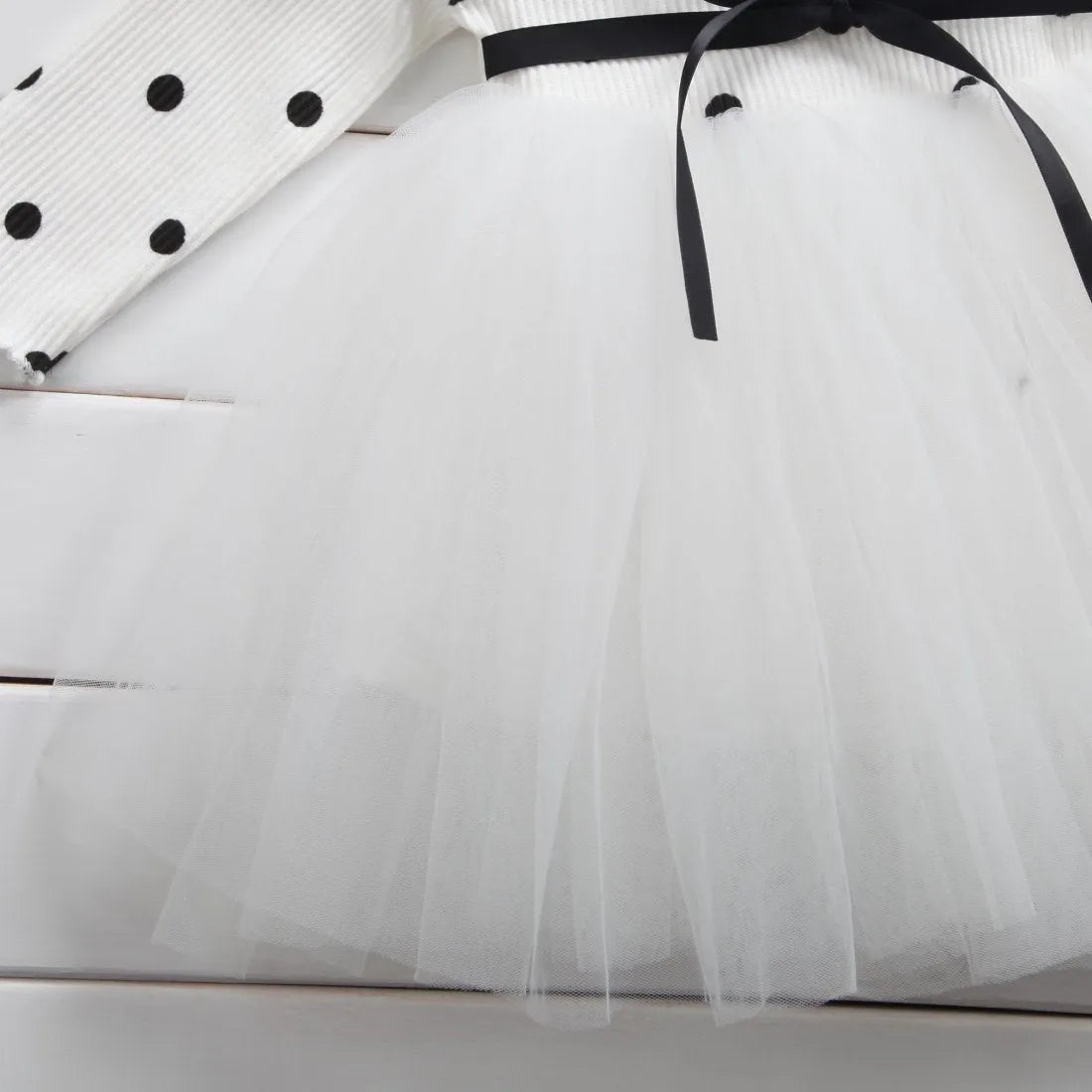 Baby girl wearing a long sleeve white lace tutu dress for a birthday or christening.