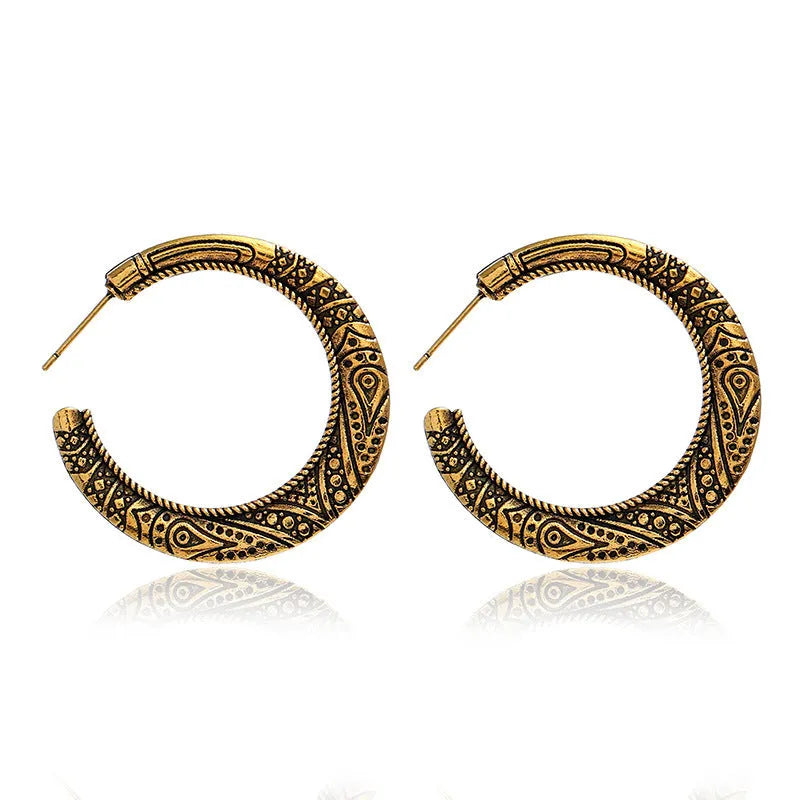 A pair of vintage-style C-shaped alloy earrings with detailed street shot engraving, shown in bronze finish.