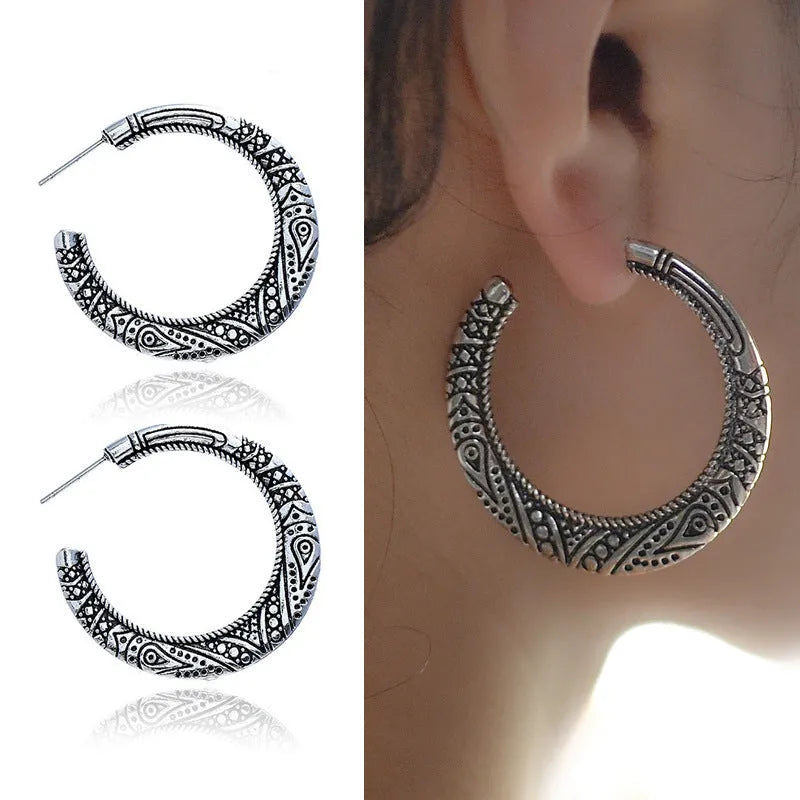 A pair of vintage-style C-shaped alloy earrings with detailed street shot engraving, shown in bronze finish.