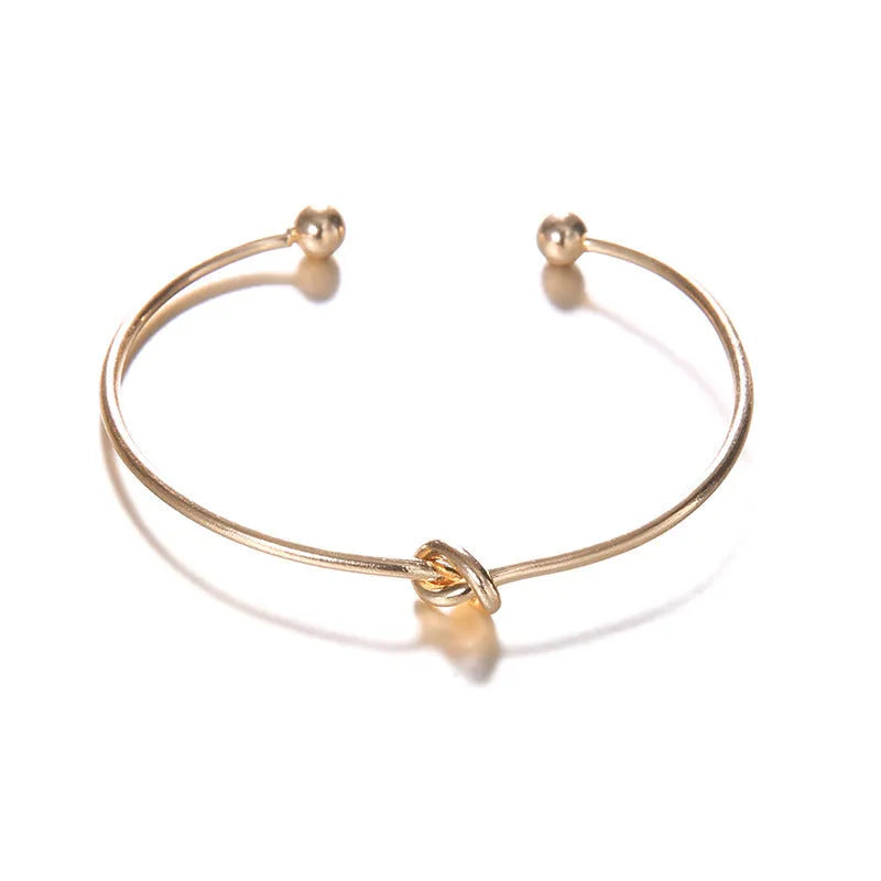 Gold vintage women's cuff bracelet with arrow and knotted design details.