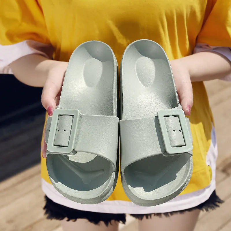 Women's grey blue buckle flip flops with a soft EVA sole on a plain background