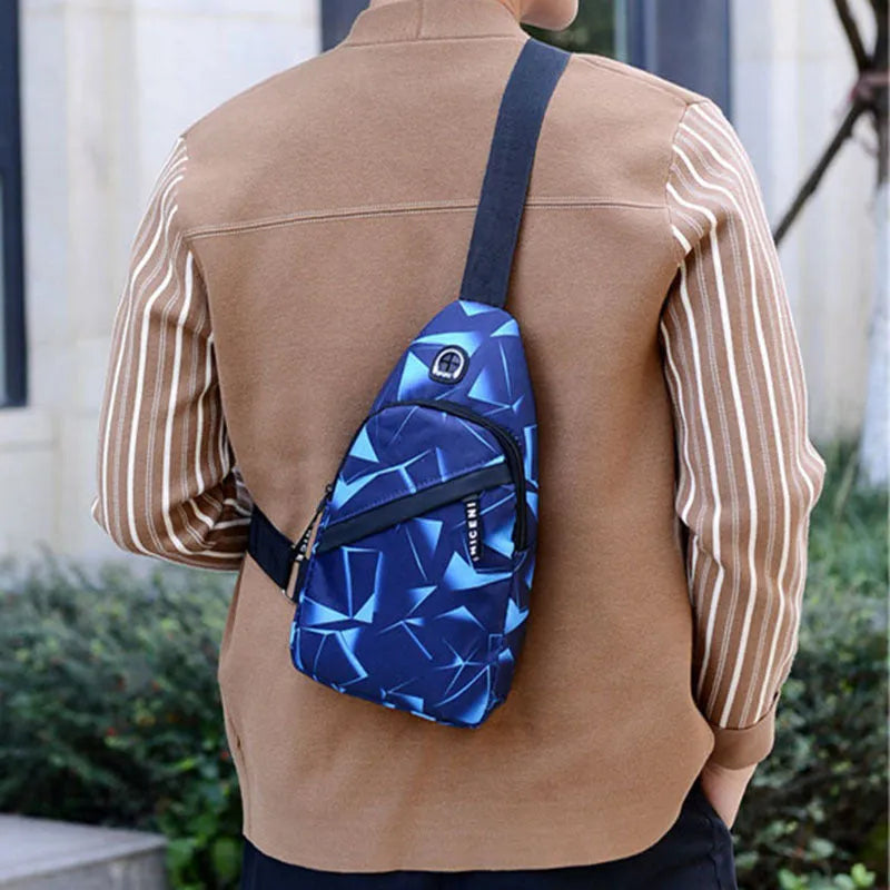 Men's blue Oxford cloth crossbody sling bag showing earphone hole and front zipper.