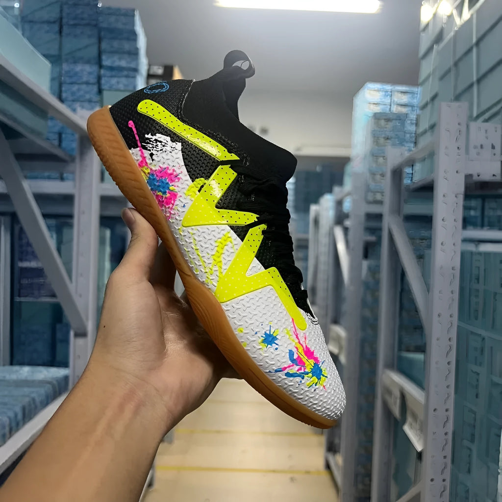 Adult low-top soccer shoes in black and yellow, showing studded rubber sole and printed PVC upper.