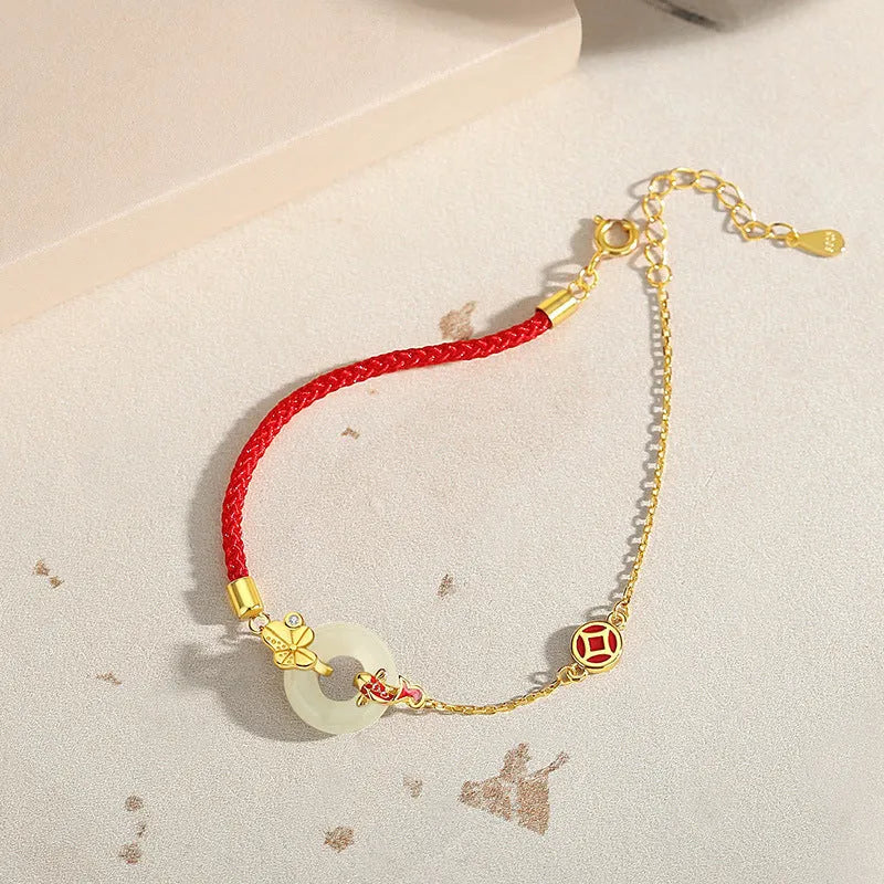 Women's silver bracelet with gold peace buckle and koi fish charm on a red rope.