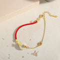 Women's silver bracelet with gold peace buckle and koi fish charm on a red rope.
