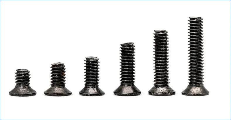 Black countersunk head machine screws for laptop repair in a box, showing cross-drive groove.