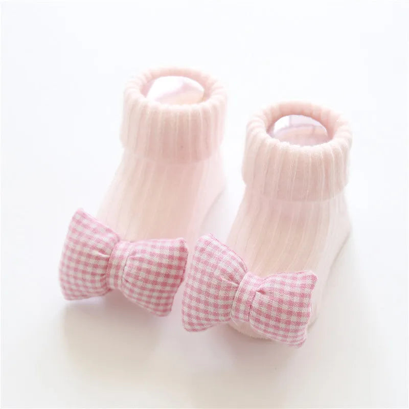 Cotton baby socks in multiple colours and prints including panda, lion, bows, and stars on a white background.