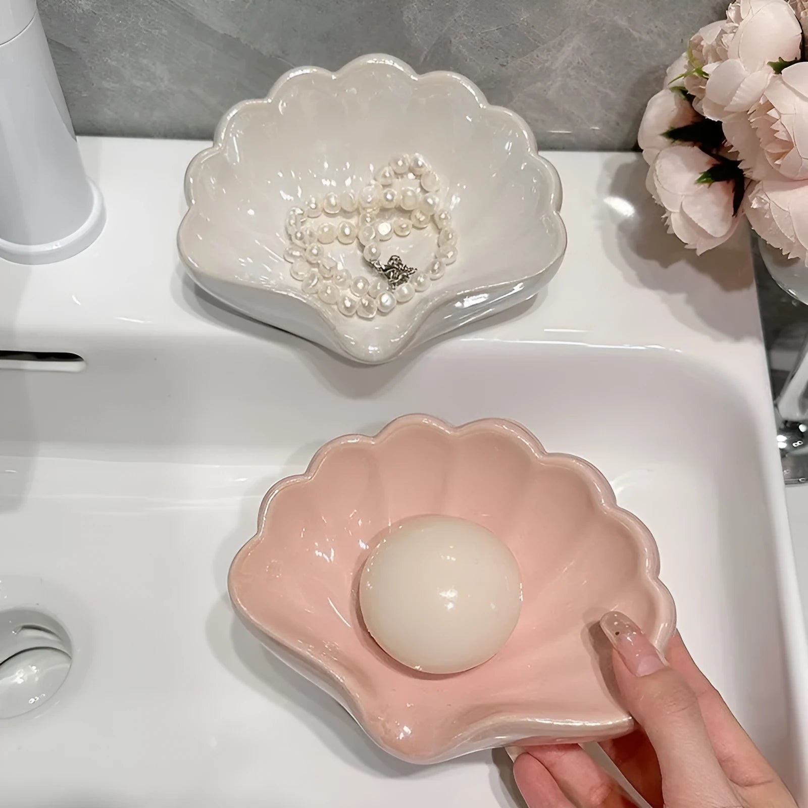 White or pink plastic shell-shaped soap dish for bathroom use.