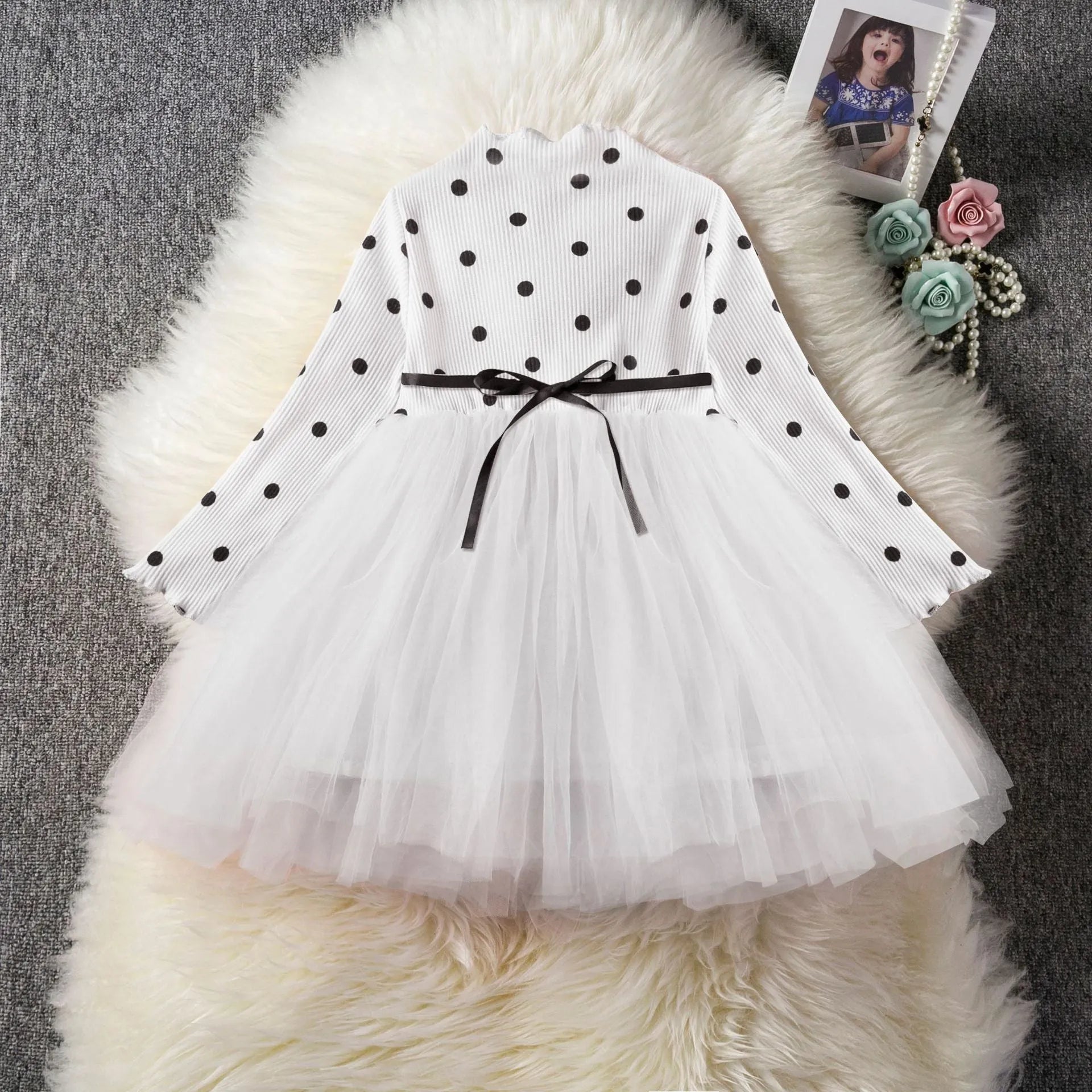Baby girl wearing a long sleeve white lace tutu dress for a birthday or christening.