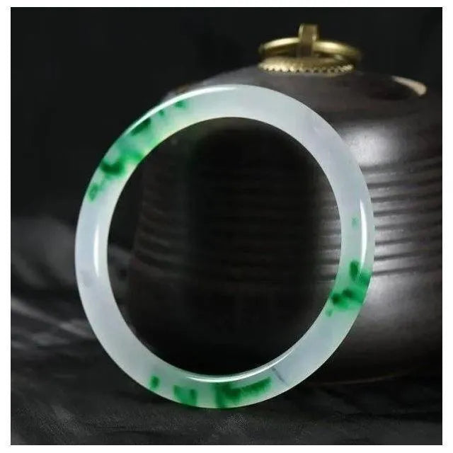 Jade bracelet with carved floating flower and auspicious cloud pattern in emerald green.