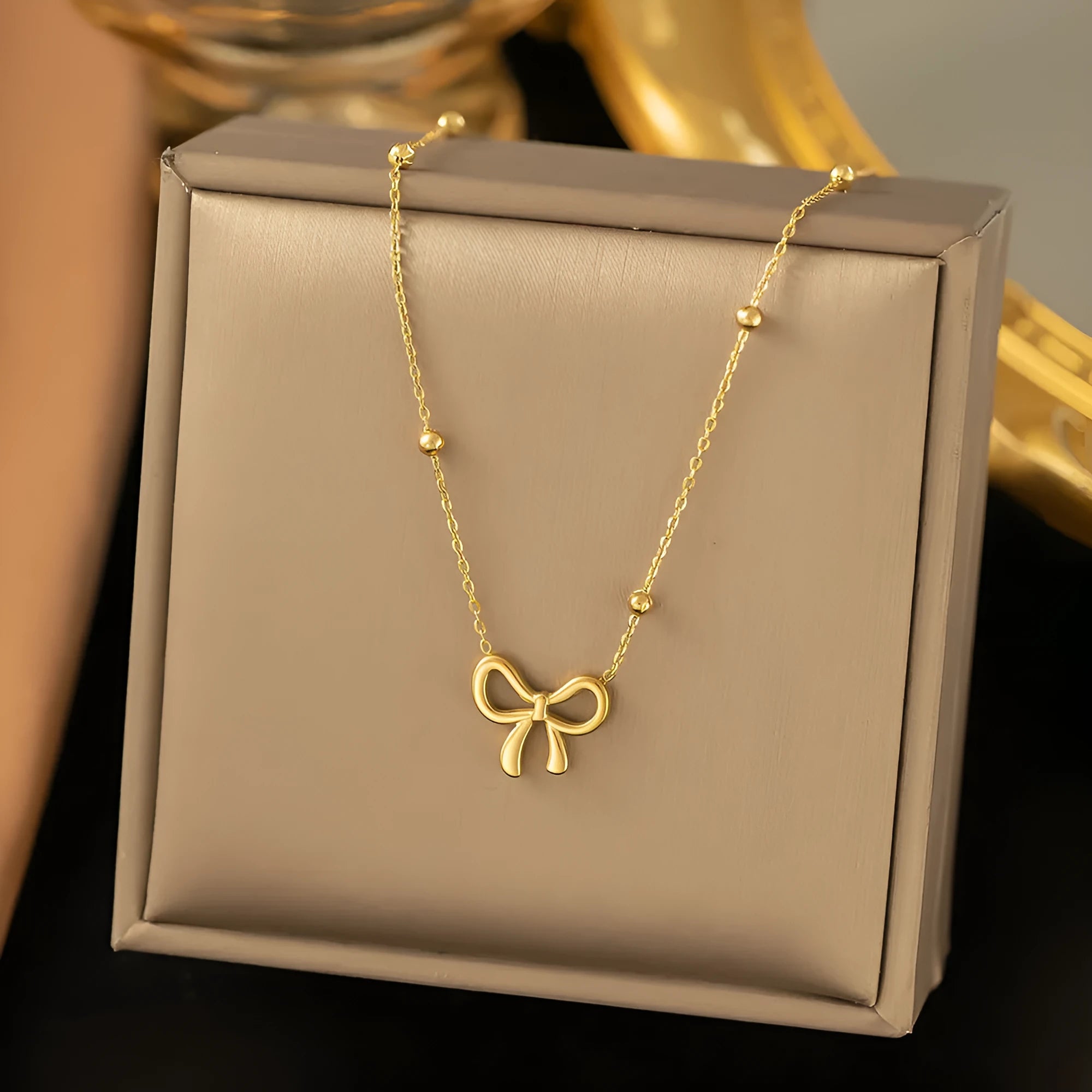 Gold electroplated bow pendant fashion necklace on a cross chain, adjustable 41-50cm.