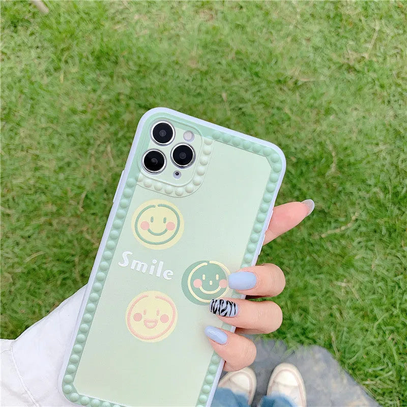 Green iPhone case with smiley face and white polka dot geometric design on the back.