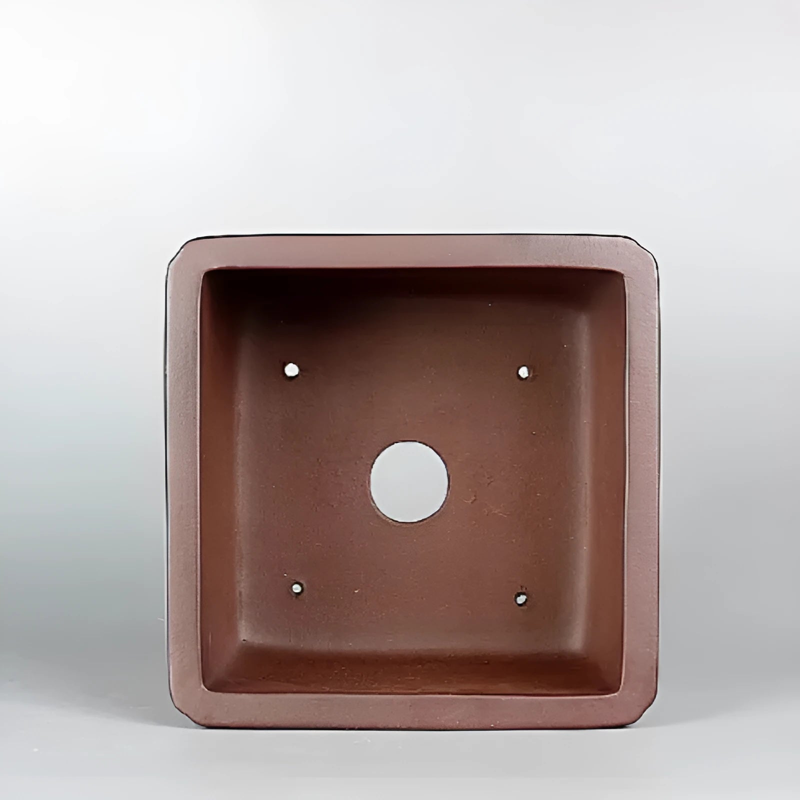 Brown handmade purple clay ceramic flower pot with antique style, shown on a surface.