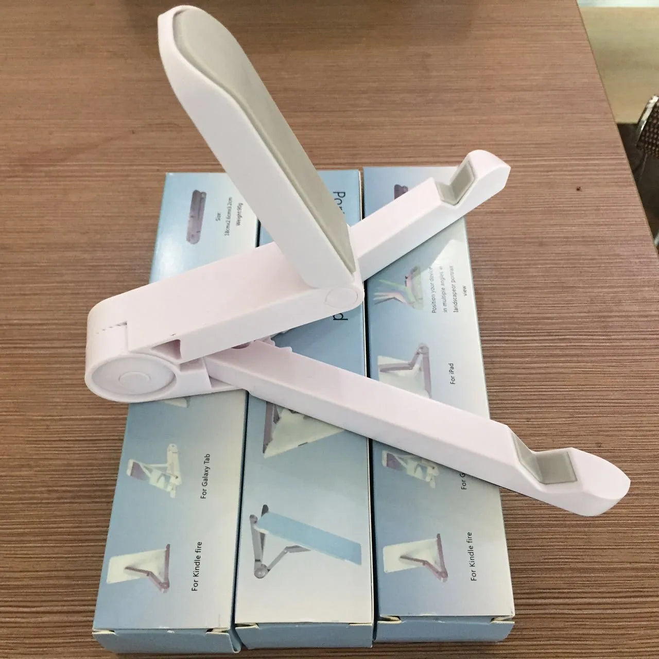 Black foldable tablet holder stand supporting a smartphone in landscape mode on a desk.