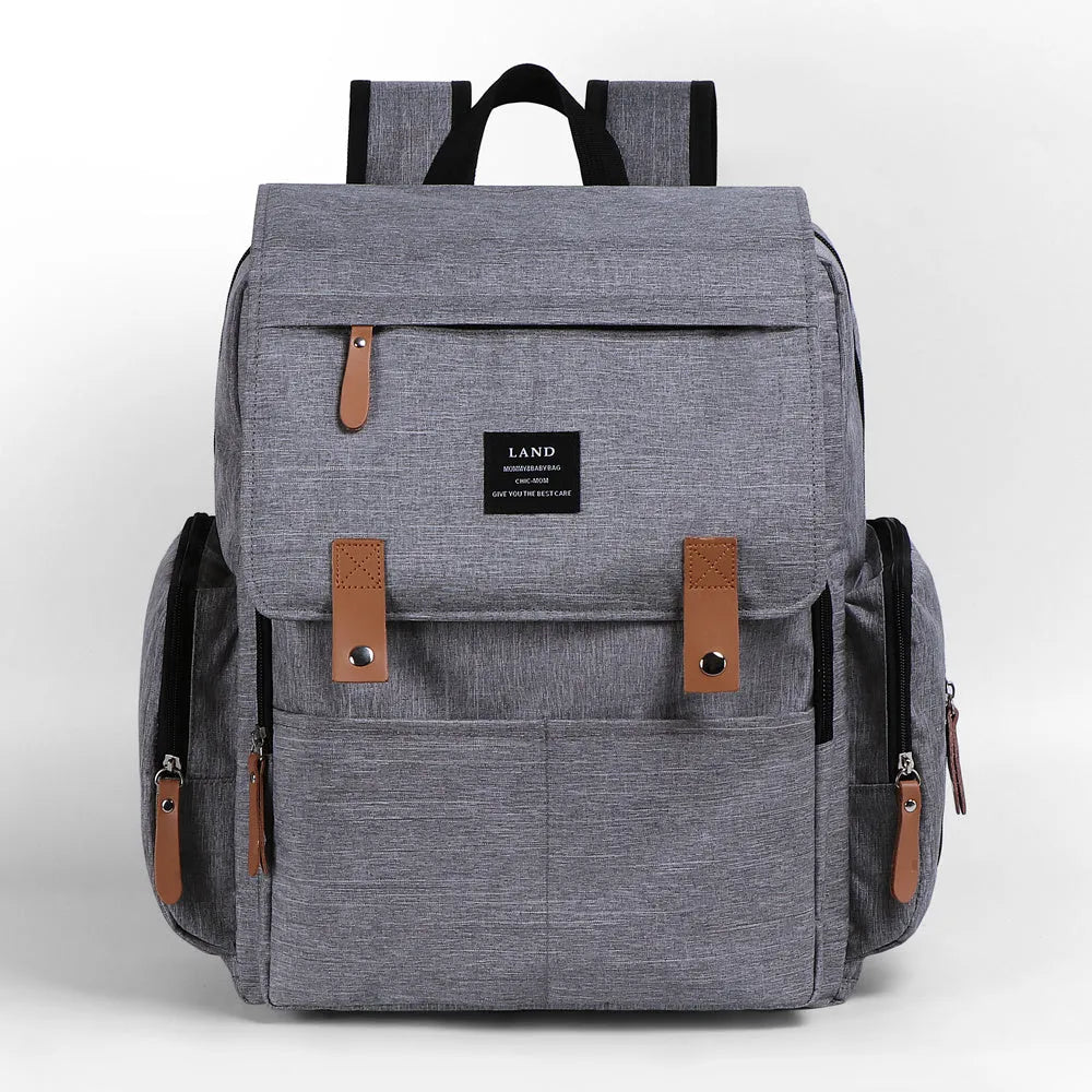 LAND Mommy large grey diaper backpack with multiple compartments and a changing mat laid out