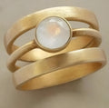 Gold titanium steel geometric ring with micro-inlaid white chalcedony stones on a hollow band.