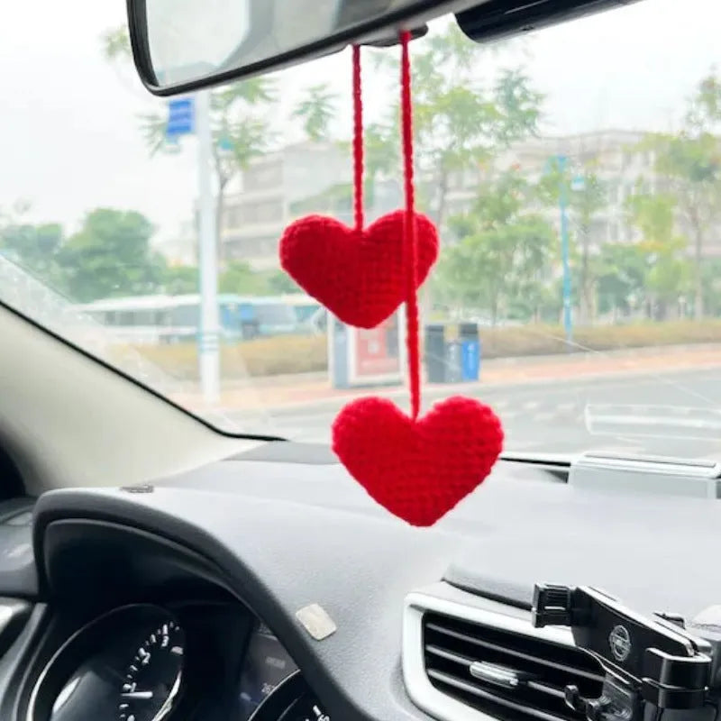 Green and white knitted wool car plant decoration with hanging rope on a car dashboard.
