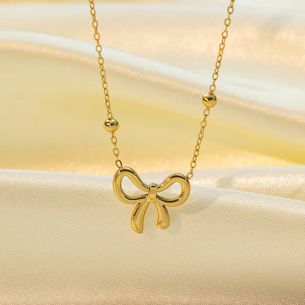 Gold electroplated bow pendant fashion necklace on a cross chain, adjustable 41-50cm.