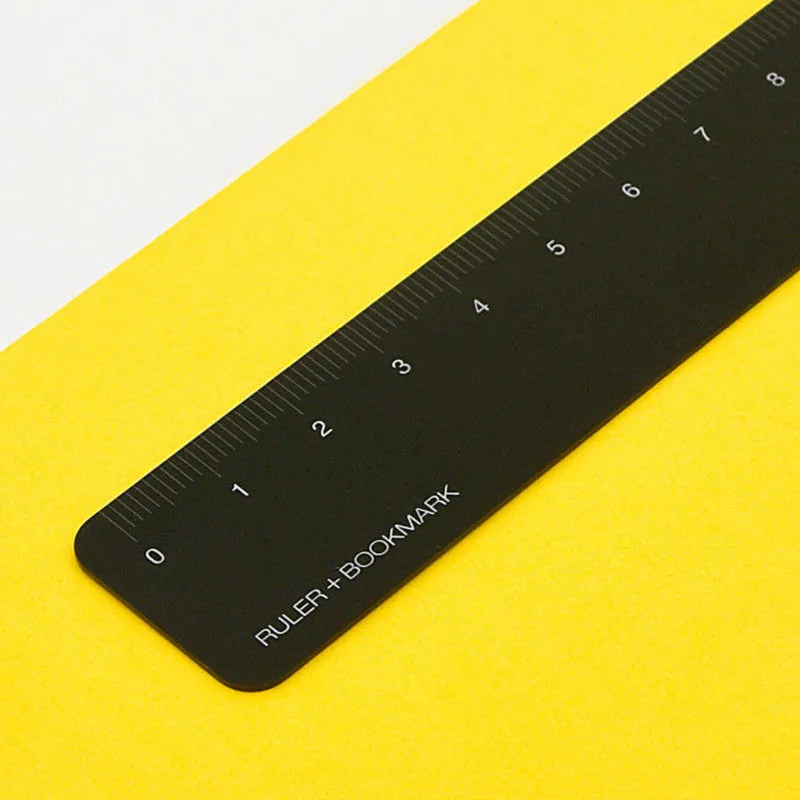 RUMA black and silver aluminium bookmark ruler showing 15cm laser-engraved scale.