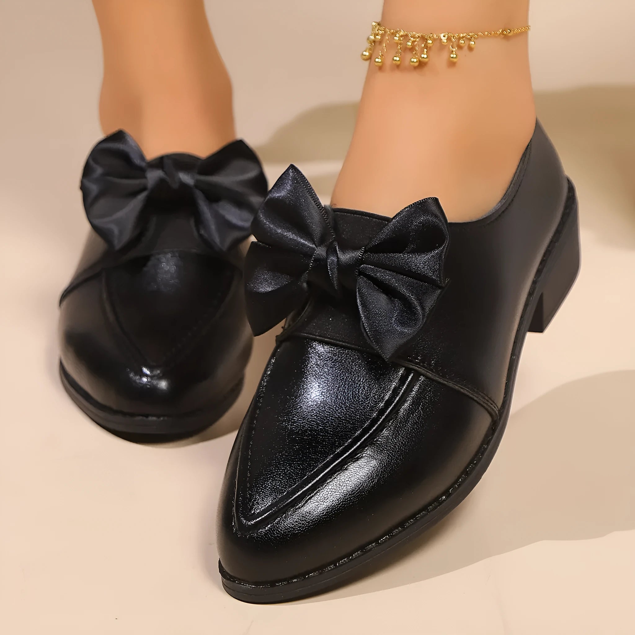 Women's brown slip-on flat shoes with a large bow decoration on the pointed toe.