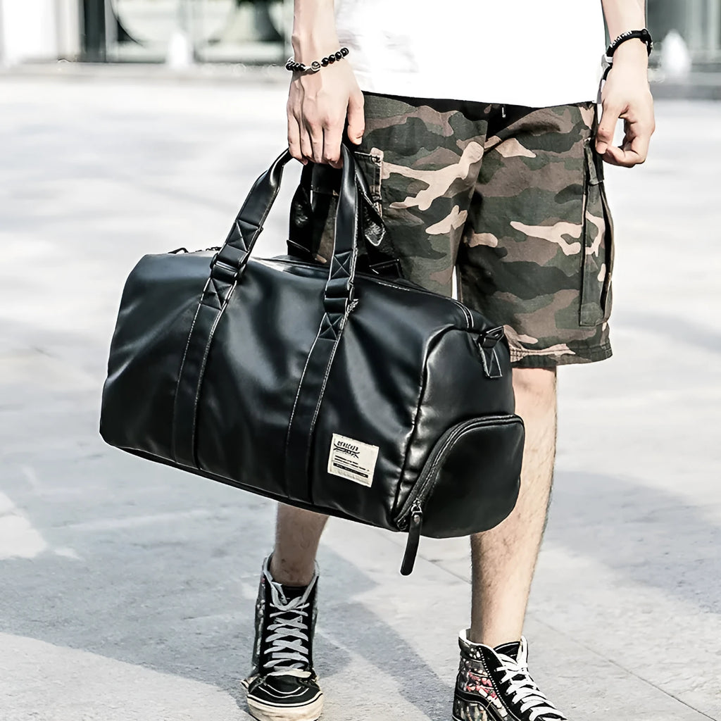 Large black PU leather sports training bag with a shoulder strap, shown with internal organiser pockets for a laptop and camera.