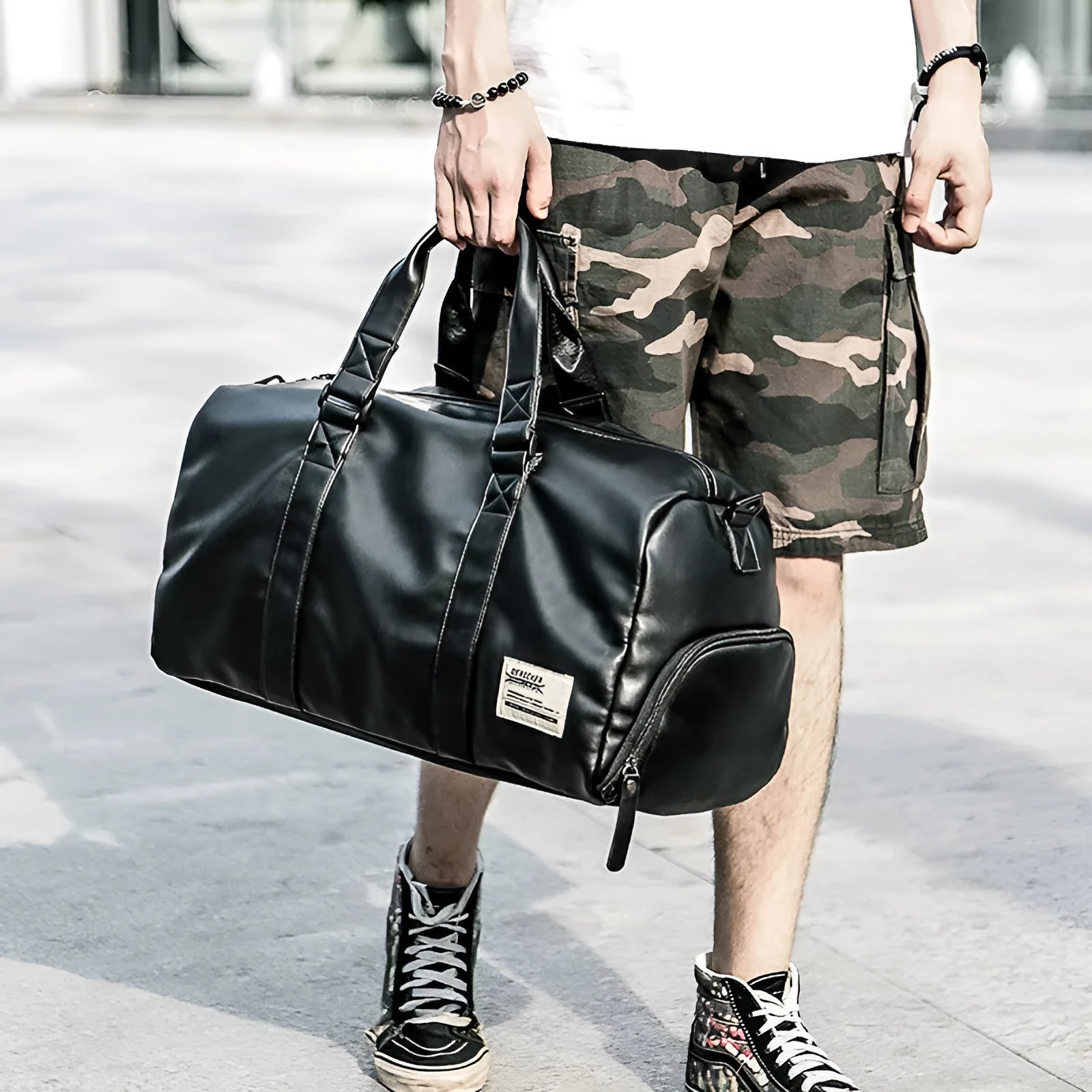 Large black PU leather sports training bag with a shoulder strap, shown with internal organiser pockets for a laptop and camera.