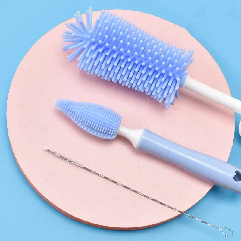 Blue, pink, and yellow silicone baby bottle brushes with an integrated straw cleaning tool.