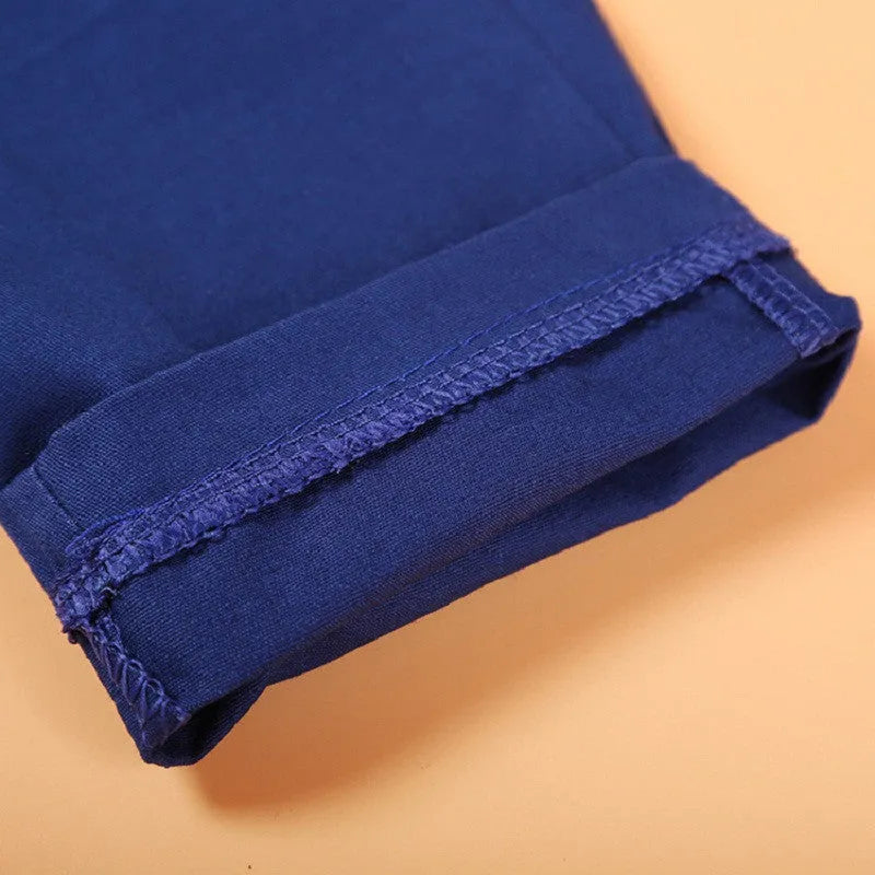 Blue boys' suit clothing set comprising a turtleneck, a vest, a tie, and trousers on a hanger.