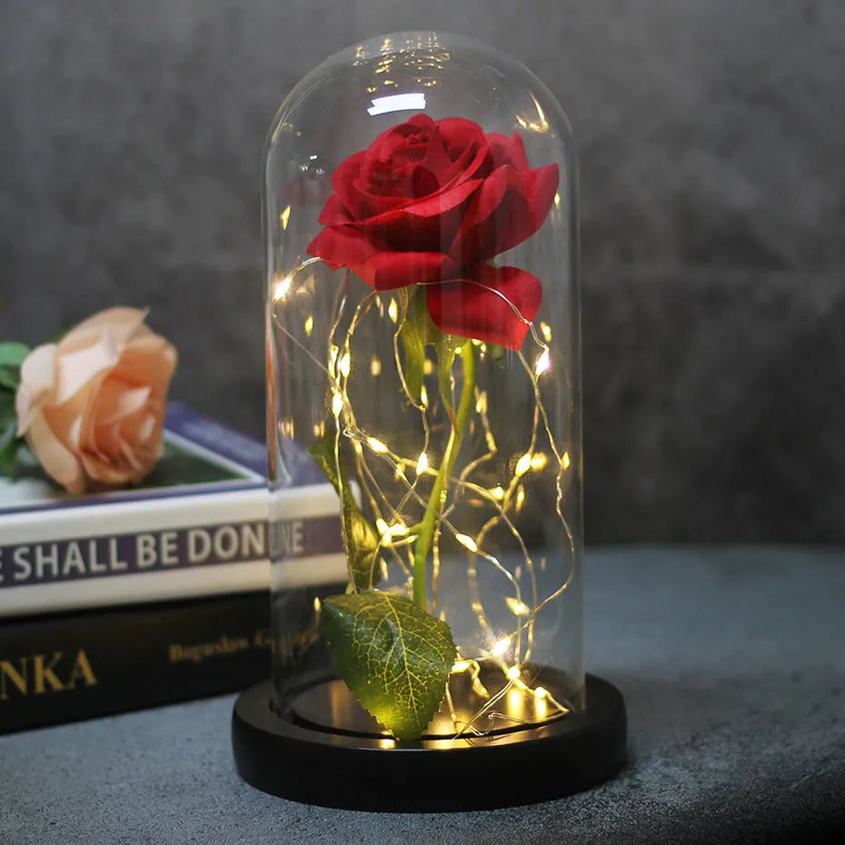 LED illuminated silk rose bouquet in a glass dome on a wooden base, with warm white lights.