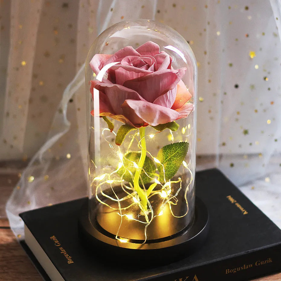 LED illuminated silk rose bouquet in a glass dome on a wooden base, with warm white lights.