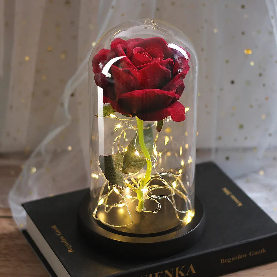 LED illuminated silk rose bouquet in a glass dome on a wooden base, with warm white lights.