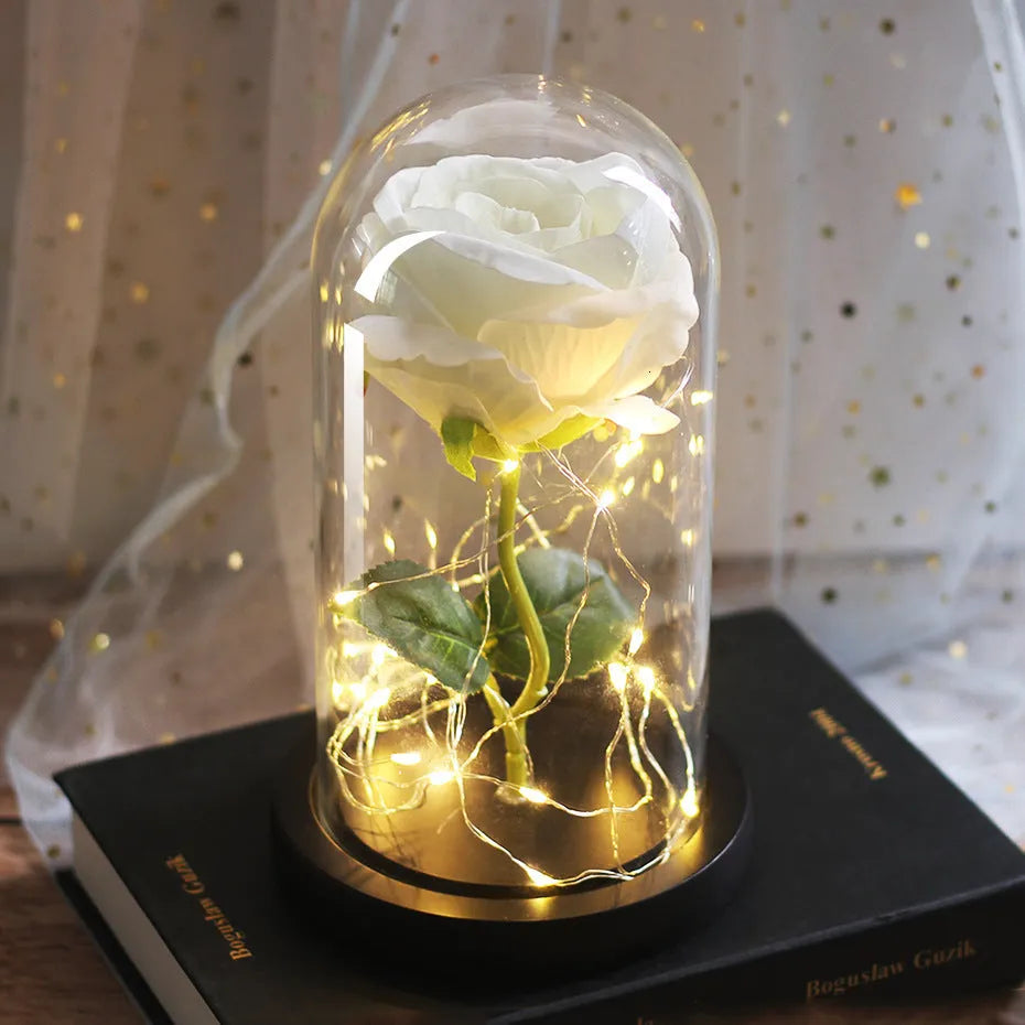 LED illuminated silk rose bouquet in a glass dome on a wooden base, with warm white lights.
