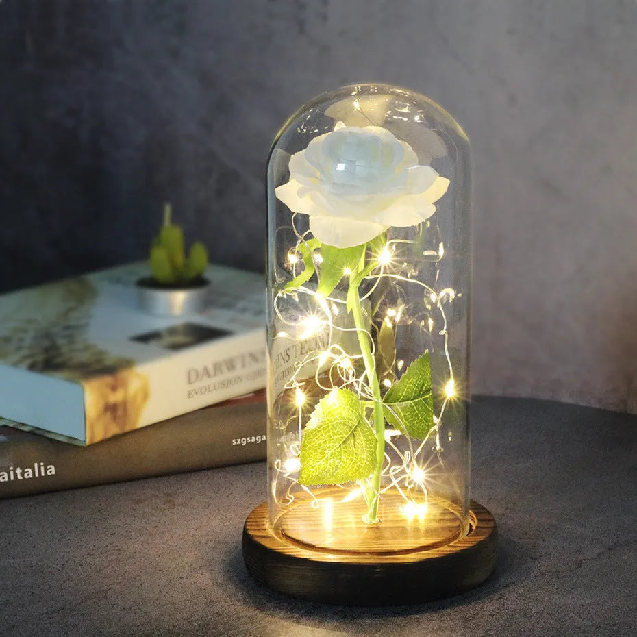 LED illuminated silk rose bouquet in a glass dome on a wooden base, with warm white lights.