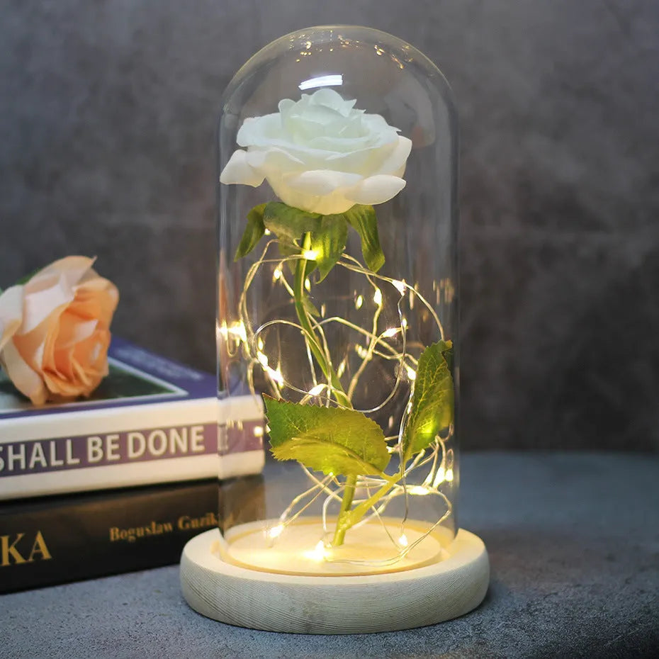 LED illuminated silk rose bouquet in a glass dome on a wooden base, with warm white lights.