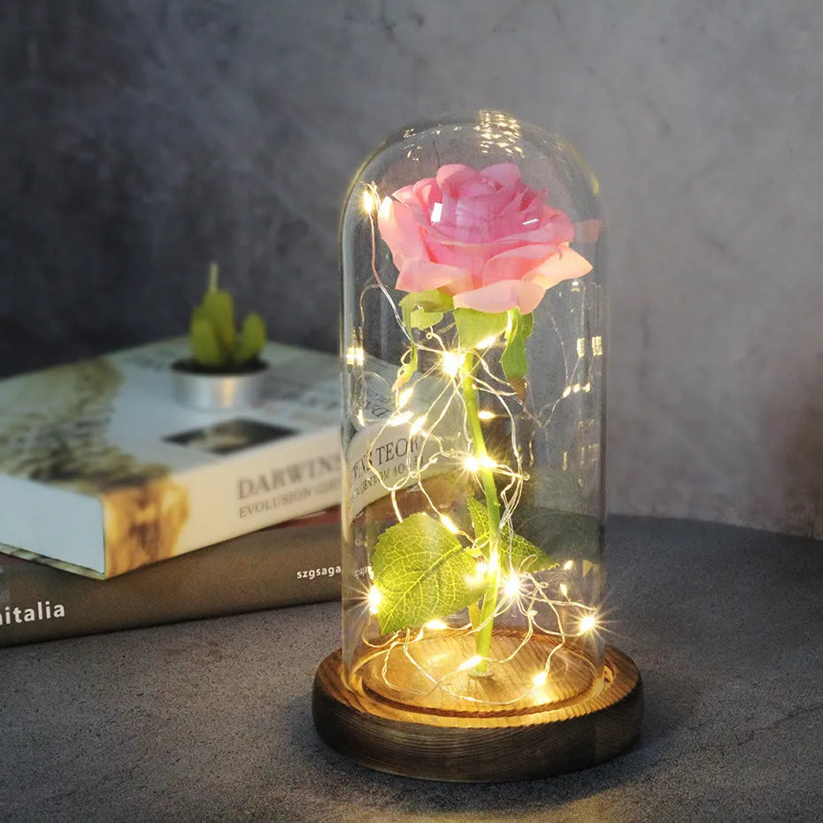 LED illuminated silk rose bouquet in a glass dome on a wooden base, with warm white lights.