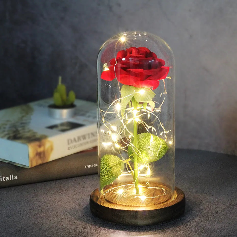 LED illuminated silk rose bouquet in a glass dome on a wooden base, with warm white lights.