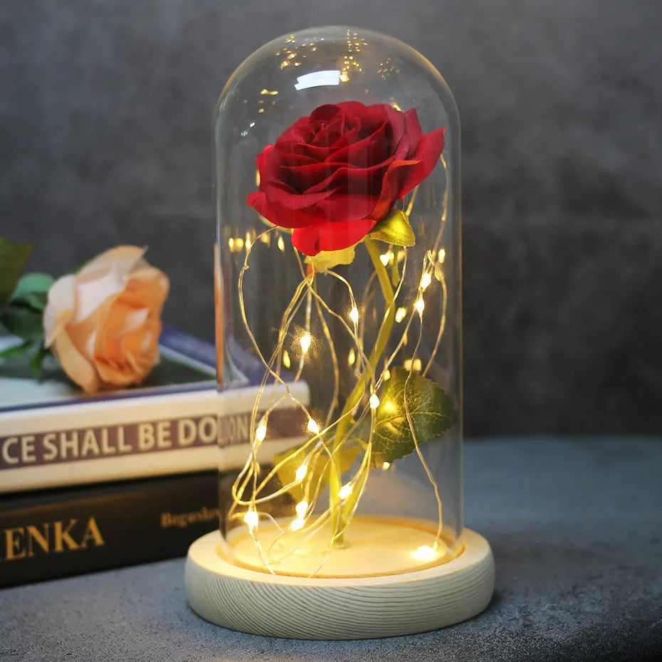 LED illuminated silk rose bouquet in a glass dome on a wooden base, with warm white lights.