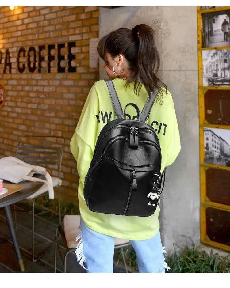 Black soft-surface leather backpack with 24-litre capacity showing ID pocket and luggage strap attachments