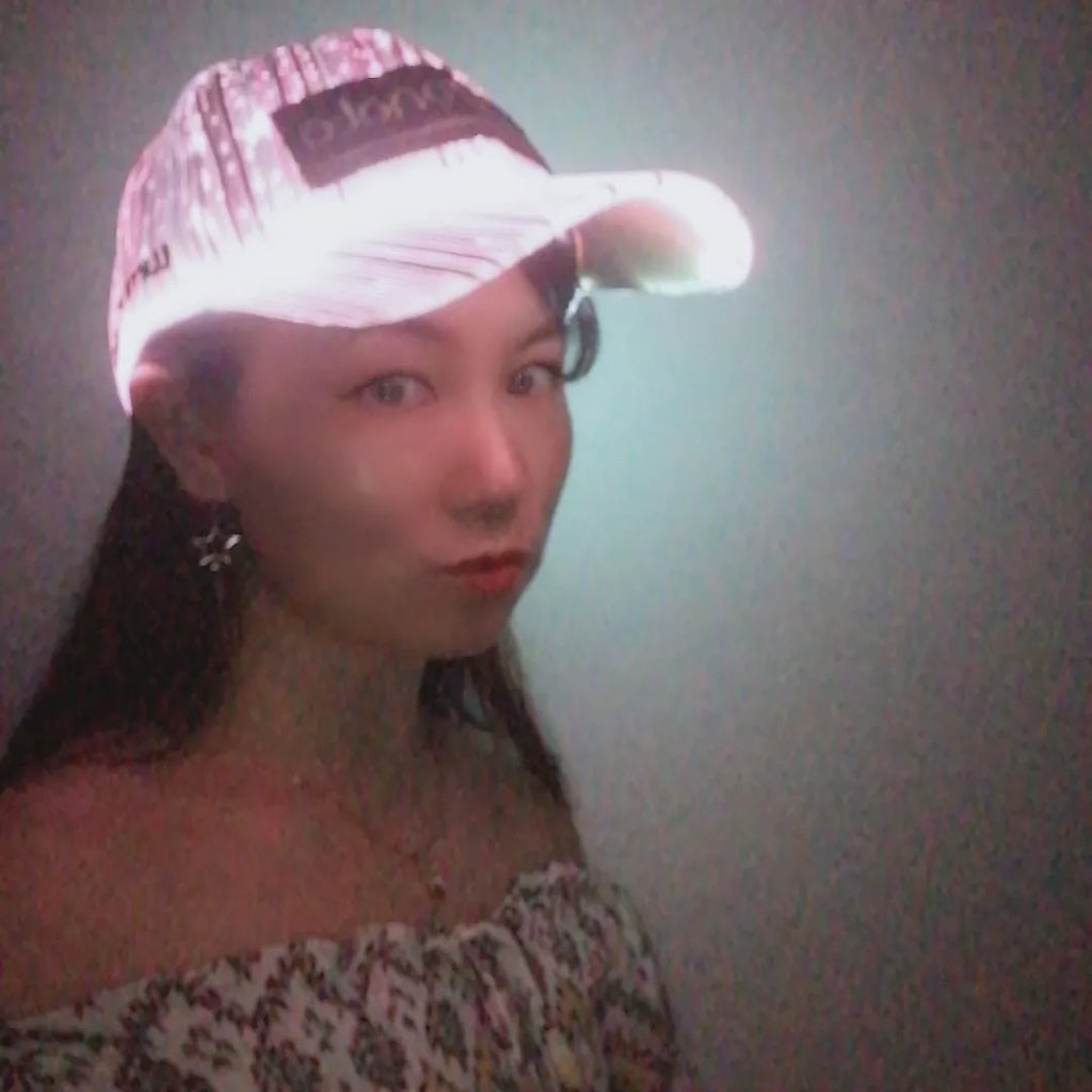 White luminous baseball cap with fibre optic fabric and LED glow against dark background
